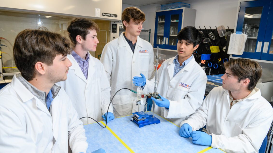 Five undergraduate students pose with the diagnostic device known as NephroGuard in a laboratory. 