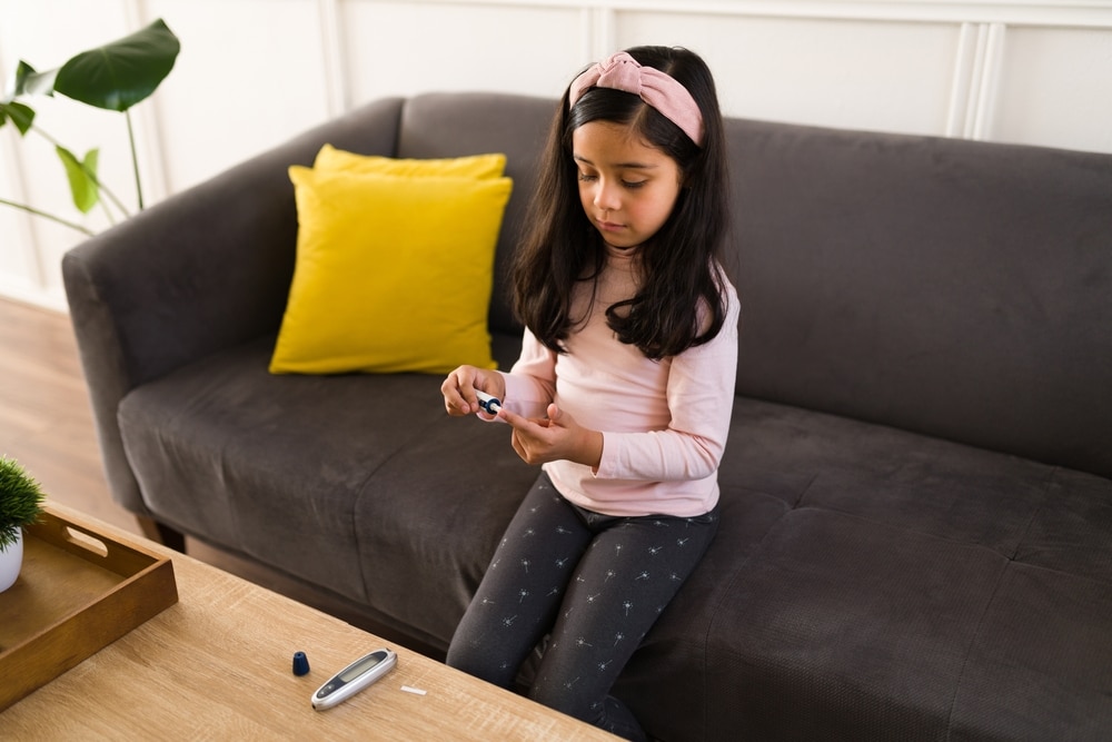 A young girl checking her blood glucose level with a blood glucose meter.