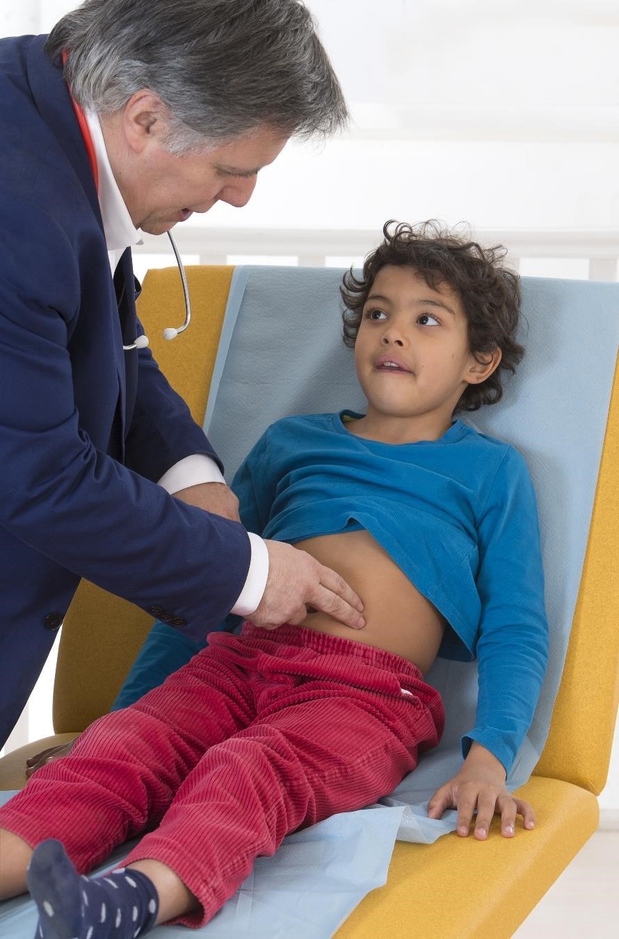 Doctor examining a child’s abdomen during a physical exam.