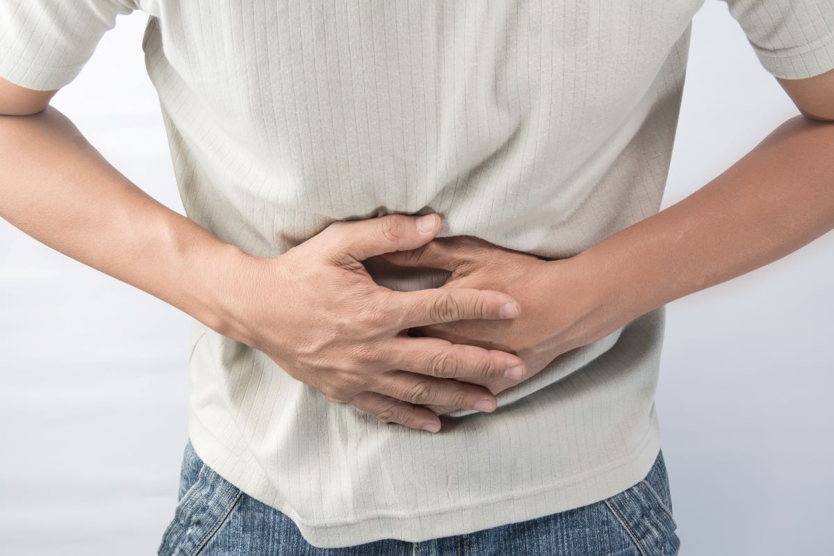 Person holding hands against stomach.