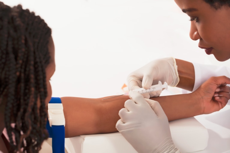 Una profesional de la salud extrayendo sangre del brazo de una mujer.