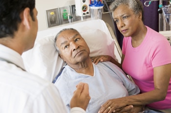  A doctor talking with a patient and his wife in a hospital room.