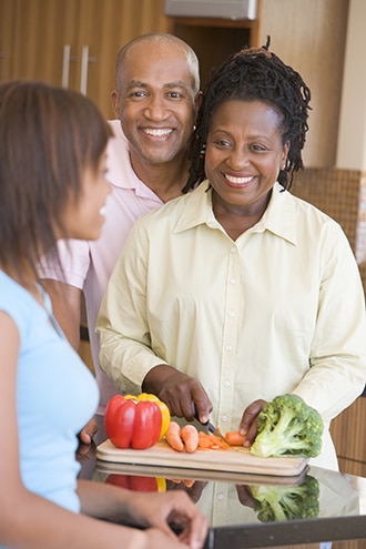 Mother, father, and daughter preparing vegetables in a kitchen